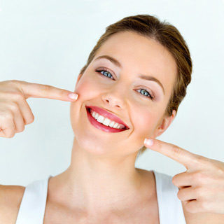 Teaser Patienten: Eine Frau deutet auf Ihre Zähne