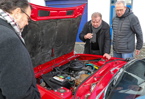 Gewinnspiel zugunsten der Kinderkrebsforschung: Dr. Unger und der Gewinner des Lancia beim Betrachten des Motors